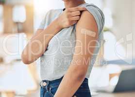 Closeup of mixed race woman wearing a bandaid plaster on her arm after getting a covid vaccine shot at a clinic or hospital. One female only strengthening immunity from flu and disease to stay healthy