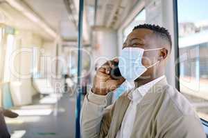 Black businessman travelling alone. A young african american businessman using a cellphone while sitting at the window on a train during his commute to the city