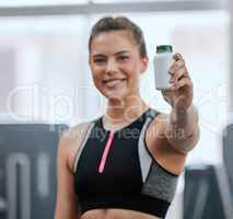 Smiling trainer alone in gym while holding and showing bottle of steroid pills. Caucasian coach with hormone enhancing drugs for workout in exercise health club. Bodybuilder woman in fitness centre