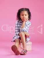 One cute little mixed race girl sitting in a studio and daydreaming against a pink copyspace background. A lonely African American child looking sad and depressed