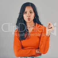 Portrait of mixed race woman isolated against grey studio background with copyspace and pouting. Beautiful young hispanic standing alone and making silly and goofy facial expression. One model posing