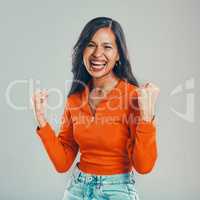 Portrait of mixed race woman isolated against grey studio background with copyspace. Young hispanic standing alone and celebrating success. Excited model making fists with hand gesture while cheering