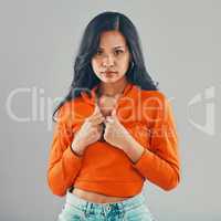 Portrait of mixed race woman isolated against grey studio background with copyspace and feeling flirty. Young, sultry, seductive hispanic standing alone. One model posing with confidence and attitude