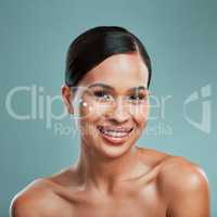Portrait of an attractive young mixed race woman posing with cream moisturiser on her face against a green studio background. Beautiful hispanic using a skin products to keep her face clean and healthy