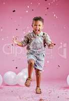 A cute little mixed race boy celebrating and winning against a pink copyspace background in a studio. African child looking excited at a gender reveal party with confetti and balloons
