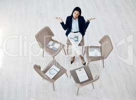 I have no clue where the rest are. High angle shot of a young businesswoman shrugging while sitting alone on a chair in a huddle in an office.