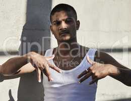 Whats good in the hood. Portrait of a young man showing gang signs against an urban background.