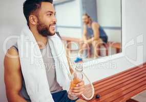 Happy friends relaxing after a match. Mixed race player drinking water after a match with his friend. Two friends talking after a squash match. Coach talking to his player in the locker room