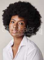 Studio portrait of a young stunning African American woman with a beautiful afro. Confident black female model showing her smooth complexion and natural beauty while posing against a grey background