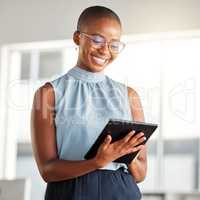 Young cheerful african american businesswoman working on a digital tablet alone at work. Happy black woman smiling while using social media on a digital tablet. Businessperson checking an email on a digital tablet