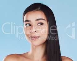 One beautiful young hispanic woman with healthy skin and sleek hair posing against a blue studio background. Mixed race model with flawless complexion and natural beauty