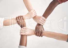 Businesspeople gripping and holding each others wrists in an office at work. Business professionals joining their arms and holding wrists in support. Coworkers huddling and staying connected by holding wrists from above