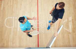 Above view of two unknown squash players standing together after playing court game. Fit active mixed race and caucasian athletes talking after training practice in sports centre. Team of sporty men