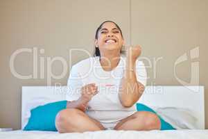 Motherhood, here I come. a young woman cheering after taking a pregnancy test at home.