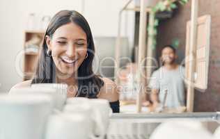 One happy hispanic waitress using a coffee machine to prepare a hot beverage in a cafe. Happy barista making a warm drink to serve customers in a coffeeshop