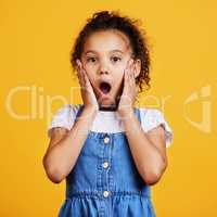 Studio portrait mixed race girl looking shocked with her hands on her cheeks isolated against a yellow background. Cute hispanic child posing inside. Surprised and amazed kid speechless in awe