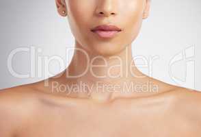 Closeup of a beautiful mixed race womans perfect neck and collar bone to model jewellery. A hispanic womans flawless pout wearing pink lipgloss against grey studio copyspace background