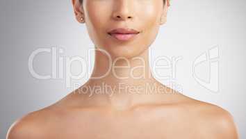 Closeup of a beautiful mixed race womans perfect neck and collar bone to model jewellery. A hispanic womans flawless pout wearing pink lipgloss against grey studio copyspace background