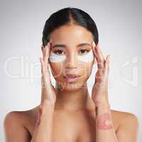 Studio Portrait of a beautiful mixed race woman wearing under eye patches. Hispanic model with glowing skin using hydrating treatment against a grey copyspace background