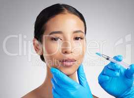 Studio portrait of a gorgeous mixed race woman getting botox filler. Hispanic model getting cosmetic surgery against a grey copyspace background