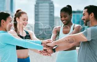 Diverse group of happy sporty people stacking hands together in pile to express unity and support. Motivated athletes huddled in circle for encouraging workout pep talk. Joining for collaboration, team spirit and dedication for training workout in city