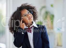 Little mind, big plans. Shot of an adorable little girl dressed as a businessperson standing alone in an office and looking contemplative.