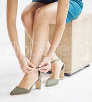 Add a touch of elegance. an unrecognizable woman putting on heels at home.