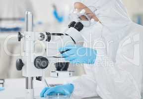 Supporting scientific investigations with detailed analysis. a scientist wearing a radiation suit while using a microscope in a lab.