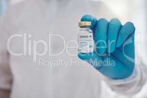 Hand of a doctor holding a vial of covid vaccine. Ready to cure the world of covid. Closeup on hands of a medical specialist holding cure to corona virus. Disease expert holding a vial of vaccine