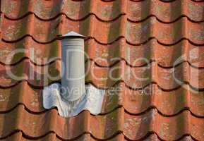 Air flow ventilation pillar and chimney on a slate roof of q house or factory building outside with copyspace. Construction of an exterior vent on rooftop for fireplace or oven smoke and heat control