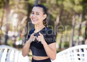 Fitness woman smiling and pointing her index fingers at the camera while out for a run at the park. Cheerful female athlete motivating you to exercise and take care of your health