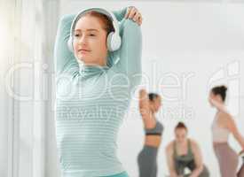 Get into the rhythm of taking care of yourself. a young woman wearing headphones while stretching.