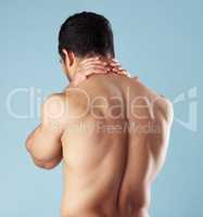 Rearview young mixed race man standing shirtless in studio isolated against a blue background. Unrecognizable topless male athlete suffering from back pain or ache. Hes picked up a fitness injury
