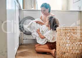 Young hispanic mother and her daughter sorting dirty laundry in the washing machine at home. Adorable little girl and her mother doing chores together at home