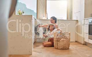 Young hispanic mother and her daughter sorting dirty laundry in the washing machine at home. Adorable little girl and her mother doing chores together at home