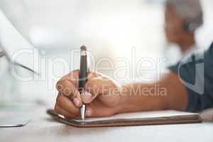 Closeup of one mixed race businessman writing notes in a book while working in at a desk in an office. Hands of entrepreneur planning schedule and brainstorming ideas in journal diary. Staying organised with to do list