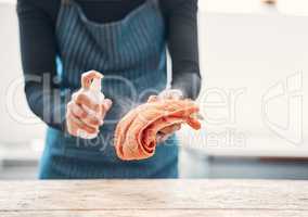 Closeup of one woman spraying antibacterial cleaner from a bottle onto a cloth to disinfect and wipe table in a cafe or store. Hands of a shop assistant sanitising surfaces to maintain hygiene and prevent the spread of covid germs