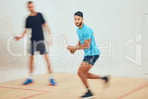 Two athletic squash players playing a game on a court with copyspace. Fit active caucasian and mixed race male athletes competing and training together in sports centre. Healthy cardio and motion blur