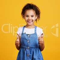 Studio portrait mixed race girl giving thumbs up isolated against a yellow background. Cute hispanic child posing inside. Happy and cute kid giving support, being positive and gesturing, I agree