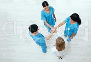 Hope in scrubs. Above shot of a group of medical practitioners joining their hands together in a huddle.