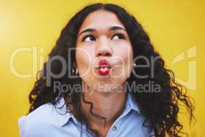 Closeup beautiful mixed race fashion woman pouting against a yellow wall background in the city. Young hispanic woman looking stylish, trendy and fashionable while making a duckface. Feeling carefree