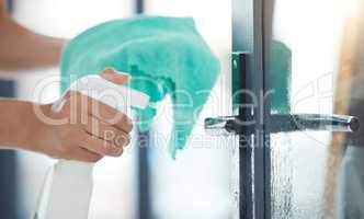 One unknown mixed race domestic worker using a cleaning product on a door handle. An unrecognizable woman enjoying doing chores in her apartment