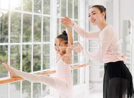 Spines of steel. a little girl practicing ballet with her teacher in a dance studio.