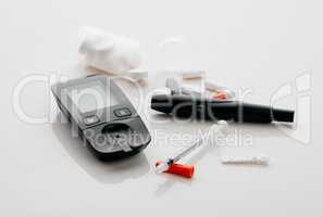 The diabetes starter pack. Closeup shot of a blood glucose meter, needles and pills in an empty studio.