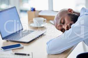 Young african american businessman sleeping at his desk at work. Tired male businessperson using a laptop while and napping on a break at work