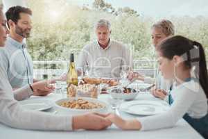 All great change begins at the dinner table. Shot of a beautiful family blessing the food with a prayer at the table together at home.