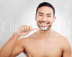 Hitting the reset button on your dental hygiene. Studio shot of a handsome young man brushing his teeth against a grey background.