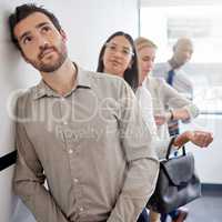 Hes got big dreams for himself. a young businessman thinking while waiting in line at an office.