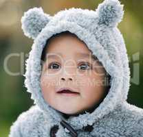 So beary cute. Shot of an adorable baby boy wearing a furry jacket with bear ears outdoors.