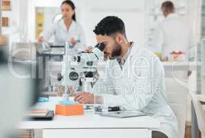 Take careful note of what you observe. a young scientist using a microscope in a lab.